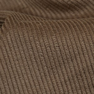 Puede incluir: Primer plano de una tela de pana marrón con una superficie texturizada y acanalada.
