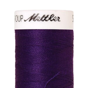 Könnte beinhalten: Eine Spule mit violettem Garn mit dem Text "Mettler Group" auf dem Etikett.