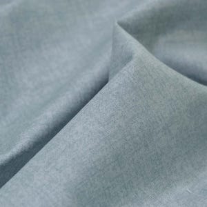 May include: A close-up of a light blue fabric with a textured surface.
