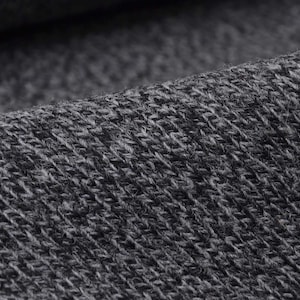May include: Detailed view of a grey knitted fabric. The material displays a diagonal weave pattern, with a blend of dark and light grey threads. The fabric looks soft and flexible, ideal for garments or home furnishings.