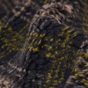 May include: Close-up of a black and yellow patterned fabric with a fuzzy texture.
