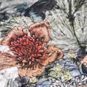 Könnte beinhalten: Nahaufnahme eines Stoffes mit Blumenmuster. Der Stoff zeigt eine große, rosafarbene Blume mit einer roten Mitte und einer strukturierten Oberfläche.