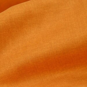 Könnte beinhalten: Nahaufnahme eines strukturierten orangefarbenen Stoffes. Der Stoff hat einen dezenten Glanz und eine leicht zerknitterte Optik.