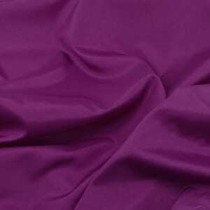 May include: A close-up of a smooth, deep purple fabric with soft folds and wrinkles.