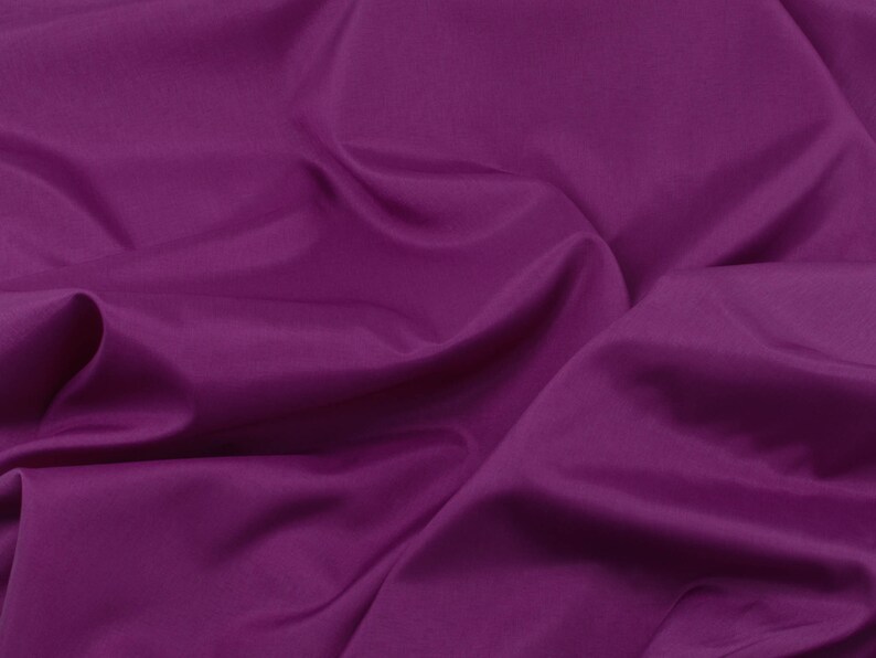 May include: A close-up of a smooth, deep purple fabric with soft folds and wrinkles.