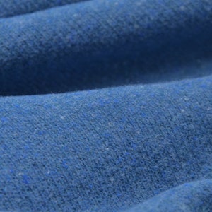 Könnte beinhalten: Nahaufnahme eines blauen Stoffes mit einer strukturierten Oberfläche. Der Stoff hat eine leicht flauschige Optik.