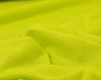 May include: A close-up of a bright green fabric with a smooth texture. The fabric is folded and wrinkled, creating a soft, flowing look.