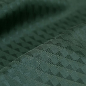 Könnte beinhalten: Nahaufnahme eines dunkelgrünen Stoffes mit einem strukturierten Muster aus kleinen Dreiecken. Der Stoff hat einen dezenten Glanz und eine weiche, glatte Textur.
