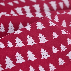 Peut inclure: Gros plan sur un tissu rouge avec un motif répété d'arbres de Noël blancs. Chaque arbre a un motif à pois. Le tissu est plié, montrant la texture et la profondeur du matériau. Idéal pour les travaux manuels de vacances.