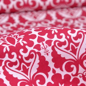 Pode incluir: Tecido vermelho com um padrão damasco branco. O tecido tem um toque macio e texturizado.