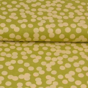 May include: Close-up of a fabric with a repeating pattern of cream-coloured circles on a green background. The fabric is folded, showing the texture and design. The pattern is evenly spaced.