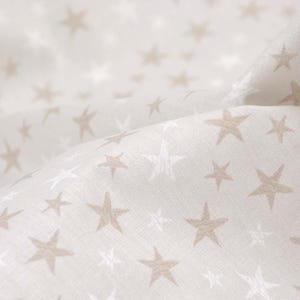 Pode incluir: Tecido branco com um padrão sutil de estrelas bege.