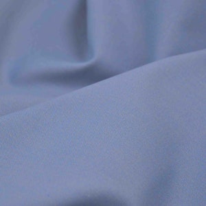 Könnte beinhalten: Nahaufnahme eines hellblauen Stoffes mit subtiler Textur. Der Stoff ist glatt und wirkt weich.