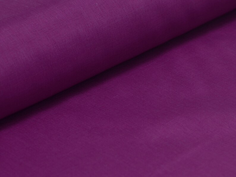 May include: A close-up of a smooth, deep purple fabric. The fabric is folded in half, creating a soft, gentle curve.