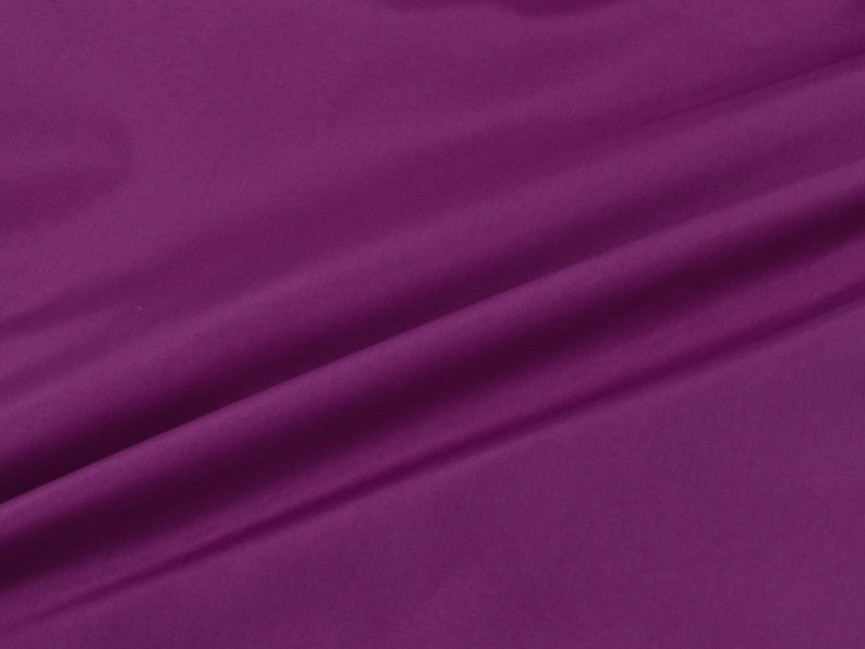 May include: A close-up of a smooth, deep purple fabric with a soft, flowing drape.