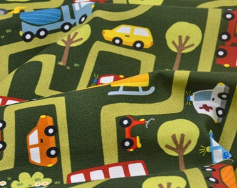 May include: Green fabric with a repeating pattern of cars, trucks, and trees on winding roads. The cars are red, yellow, blue, and white. The trucks are blue and white. The trees are green.