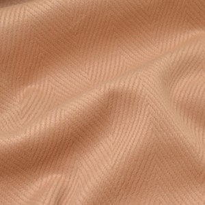 Puede incluir: Primer plano de una tela suave de color beige con un patrón de espiga.