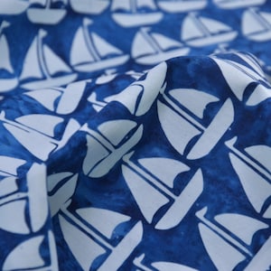 May include: Blue fabric with a white sailboat pattern. The fabric is textured and has a slightly faded look.
