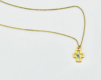 May include: A gold chain necklace with a small gold cross pendant featuring a blue stone in the center.
