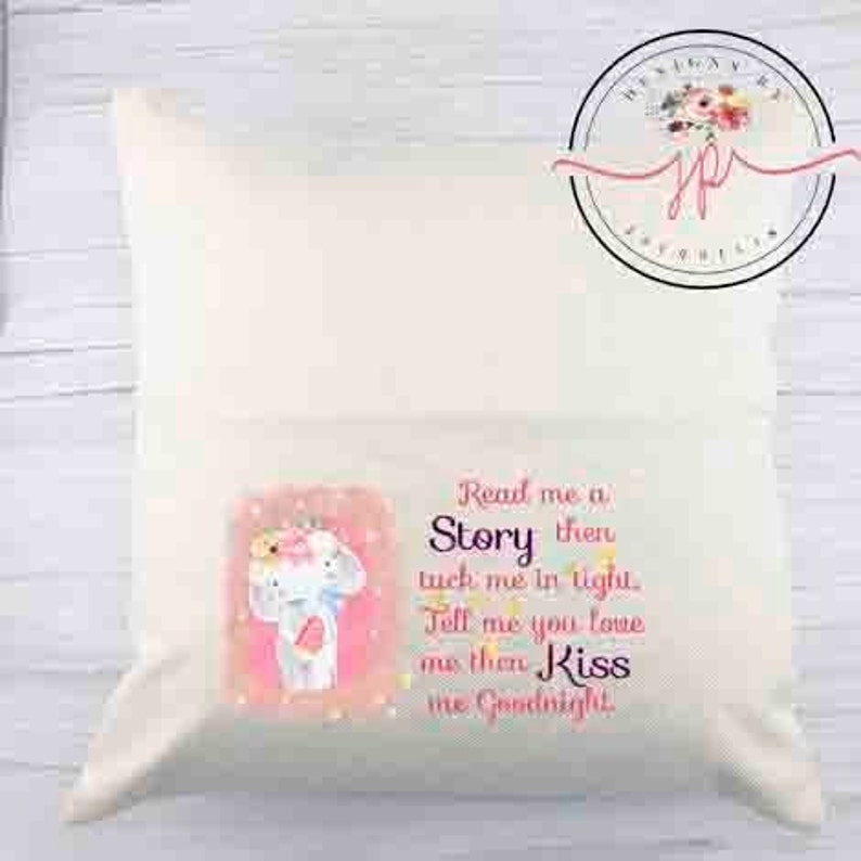 Peut inclure: Un oreiller blanc avec une illustration rose et blanche d'un &eacute;l&eacute;phant portant une couronne de fleurs. L'oreiller porte l'inscription "Read me a Story then tuck me in tight. Tell me you love me then Kiss me Goodnight".