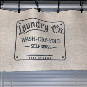 May include: A white canvas valance with black text that reads "Laundry Co. WASH. DRY. FOLD - SELF SERVE - OPEN 24 HOURS".