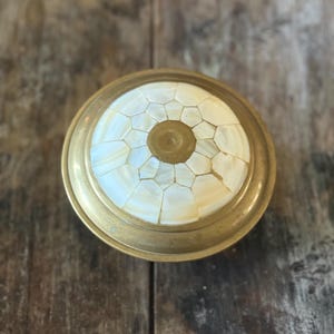 May include: A round brass trinket box with a lid inlaid with a mosaic of white mother-of-pearl tiles.