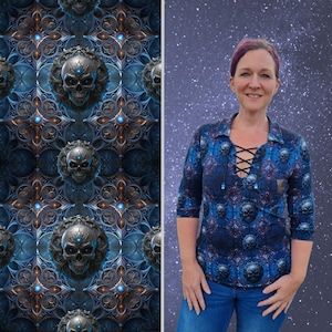 Könnte beinhalten: Eine Frau trägt ein blaues und schwarzes Shirt mit einem Totenkopf-Muster. Das Shirt hat einen Schnürkragen und das Muster erinnert an gotische Architektur. Der Hintergrund ist ein verschwommenes Bild eines sternenklaren Nachthimmels.