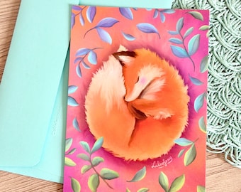 Peut inclure: Une carte de vœux rectangulaire présentant une illustration numérique d'un renard orange enroulé sur lui-même, dormant sur un fond rose vif entouré de feuilles bleu clair et vertes, avec une enveloppe bleu clair assortie.