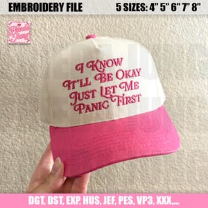 May include: A baseball cap with a white crown and a pink brim. The cap features the embroidered phrase, "I KNOW IT'LL BE OKAY JUST LET ME PANIC FIRST" in pink script. The cap is available in 4", 5", 6", 7", and 8" sizes.