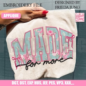Könnte beinhalten: Ein beiger Stoff mit dem Wort "MADE" in großen Blockbuchstaben, gefüllt mit einem Blumenmuster aus rosa Rosen und türkisfarbenen Blättern. Darunter stehen die Worte "for more" in Schreibschrift. Das Design ist eine Stickdatei.