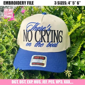 Peut inclure: Une casquette de baseball crème avec une visière bleue, brodée du texte "There's NO CRYING on the boat" en bleu et noir. La casquette comporte une étiquette sur la visière avec le texte "OTTO CLASSIC FIT OSFM MID PROFILE".