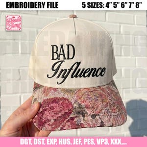 May include: Cream-colored baseball cap with the embroidered text "BAD Influence" in black. The brim features a floral pattern in shades of pink, red, and brown. The cap is available in 5 sizes: 4", 5", 6", 7", and 8".