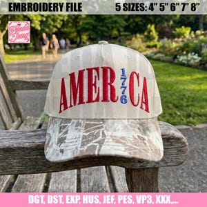 Könnte beinhalten: Baseballkappe mit dem Wort "AMERICA" in Rot gestickt, mit "1776" in Blau. Die Kappe hat einen Camouflage-Schirm und eine beige-weiß gestreifte Krone. Der Text "EMBROIDERY FILE" und "5 GRÖSSEN: 10cm 13cm 15cm 18cm 20cm" ist ebenfalls enthalten.