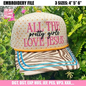 Könnte beinhalten: Eine cremefarbene Baseballkappe mit orangefarbenen Punkten und dem gestickten Text ALL THE PRETTY GIRLS LOVE JESUS. Die Kappe hat einen orangefarbenen Rand und einen braun-weiß gestreiften Schirm mit zwei blauen Ziernähten. Text: 3 SIZES: 4" 5" 6".