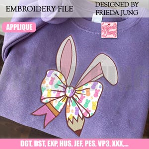 May include: A lilac-colored sweatshirt featuring an embroidered Easter bunny design. The design includes bunny ears, a bow with Peeps, and a pencil. Text on the image reads "EMBROIDERY FILE", "APPLIQUE", and "DESIGNED BY FRIEDA JUNG".
