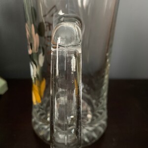 May include: A clear glass mug with a handle. The mug has a decorative design on the side.