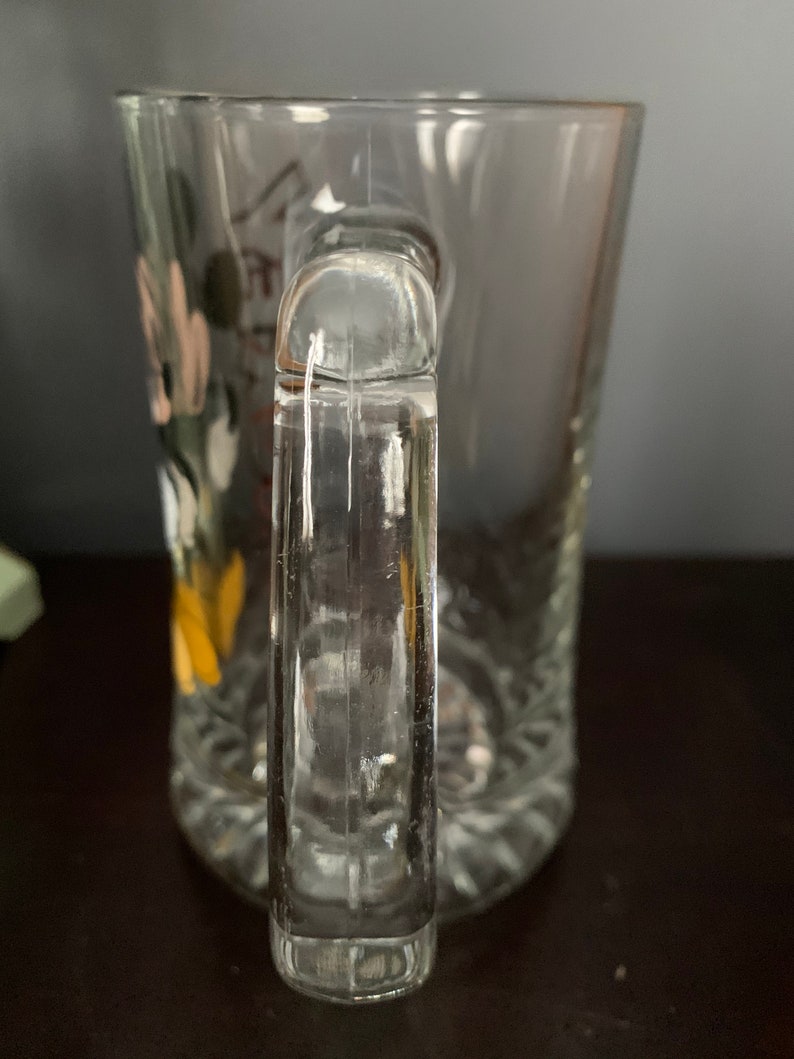 May include: A clear glass mug with a handle. The mug has a decorative design on the side.