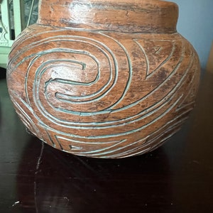 May include: A brown ceramic pot with a carved spiral design.