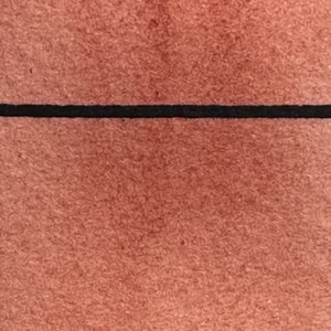 May include: A close-up of a textured, reddish-brown surface with a thin black line across the middle.