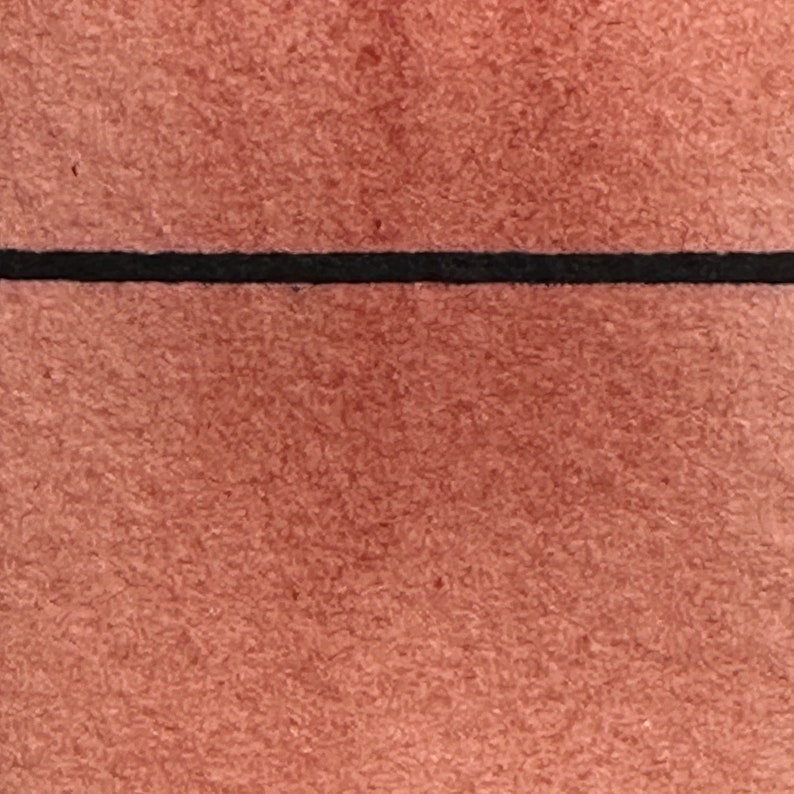 May include: A close-up of a textured, reddish-brown surface with a thin black line across the middle.