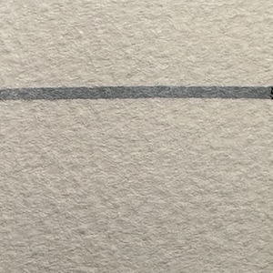 May include: A close-up of a textured, off-white surface with a single, thin, grey line running horizontally across the middle.