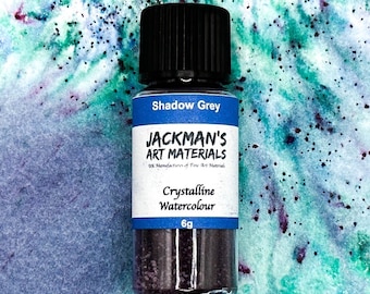 May include: A small glass bottle of Shadow Grey crystalline watercolor paint by Jackman's Art Materials. The bottle contains 6 grams of paint and is labeled with the company's name and logo.