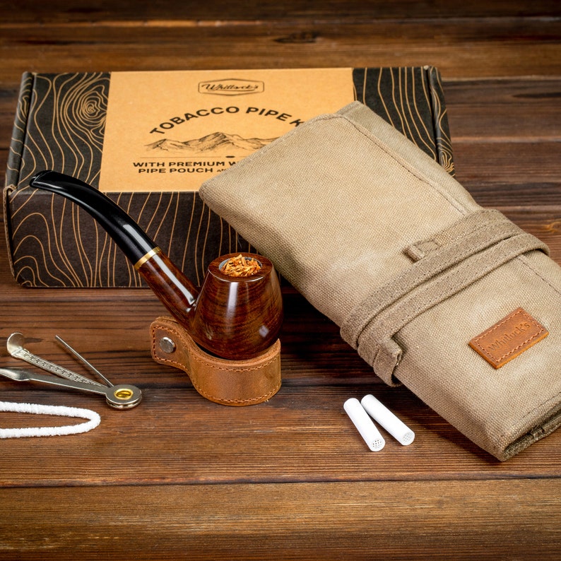 May include: A tobacco pipe kit with a wooden pipe, a leather pouch, a pipe cleaning tool, and a canvas pouch with the text "Willsboro's" on it.