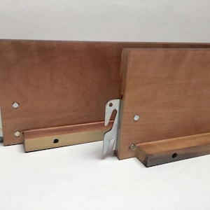 May include: Two wooden bed slats with metal brackets. The slats are light brown and have a smooth finish. The brackets are silver and have a simple design.