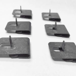 May include: Six metal clips with a small metal pin on each. The clips are designed to hold items together.