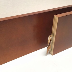 May include: Two wooden bed rails with metal brackets. The rails are a dark brown color and have a smooth finish. The brackets are a light brown color and have a simple design.