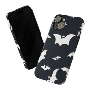 May include: A black phone case with a white bat pattern. The case has a camera lens cutout and a black background.
