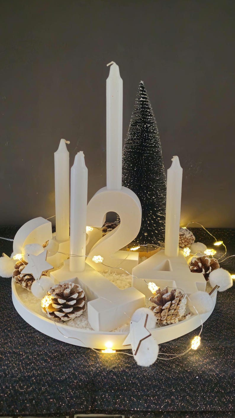 Adventskranz ganz in weiß, mit weißen Buchstaben von 1-4 auf einem weissen Tablett, alles wurde aus  hochwertigem Gießbetonpulver hergestellt.Geschmückt wird es von einem Kunstschnee, einem Tannenbaum und einer Lichterkette mit Sternen und Zapfen