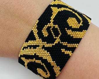 Handgjort armband med svarta och guldfärgade pärlor – Breda vävda smycken med elegant virveldesign
