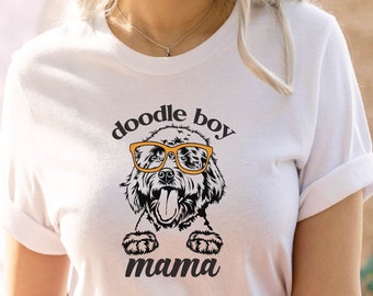 Puede incluir: Camiseta blanca con un gráfico de doodle boy mama. El gráfico presenta un doodle de un perro con gafas de sol naranjas.